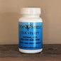A white plastic bottle with blue label and black letters of Top Shelf Elk Velvet pain relief supplement with website url at the bottom, sitting on a dark wooden surface against a beige wall.